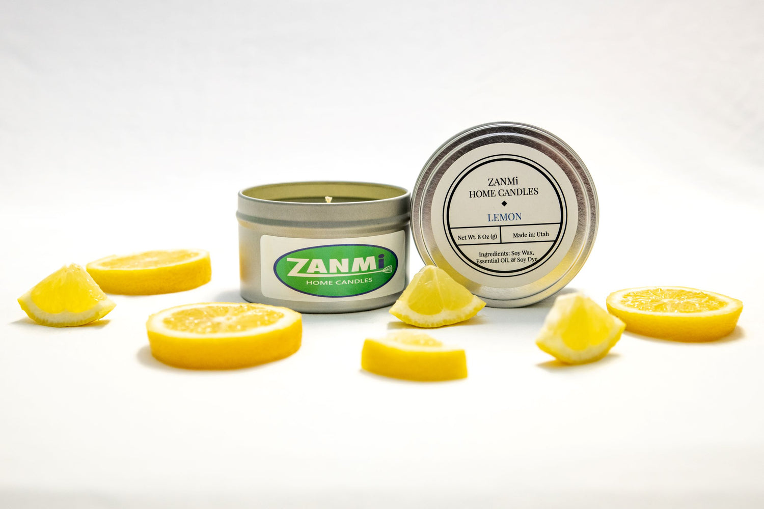 A lemon-scented soy wax candle on a white surface surrounded by lemon slices.